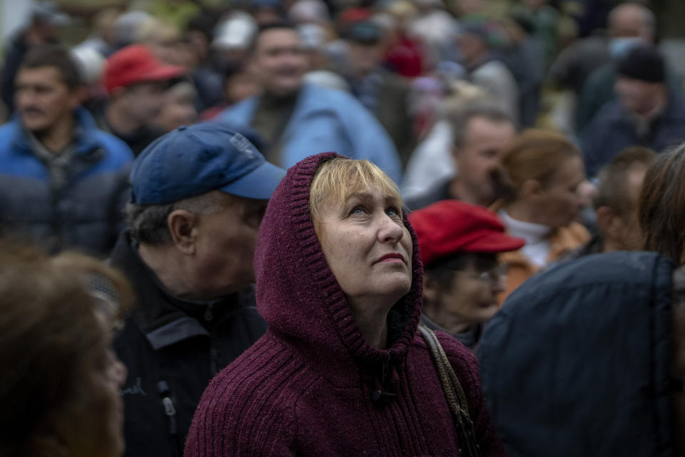 A woman looks up as she queues with others to receive a daily ration of bread, in a school in Mykolaiv, Tuesday, Oct. 25, 2022. Mykolaiv residents pick up bread from the only food distribution point in Varvarivka, a Mykolaiv district where thousands of people live. One person is allowed to receive free bread just once in three days. (AP Photo/Emilio Morenatti)