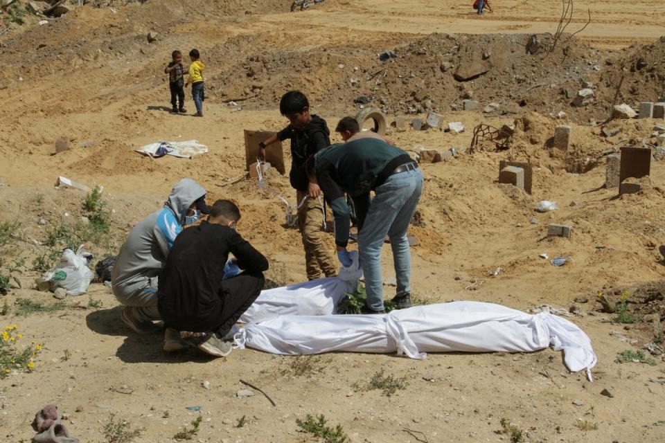 Palestinians cover a body, which was buried in a mass grave in northern Gaza, in mid-April (REUTERS)