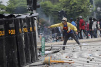 A protester taunts a line of police during clash in Jakarta, Indonesia, Thursday, Oct. 8, 2020. Thousands of enraged students and workers staged rallies across Indonesia on Thursday in opposition to a new law they say will cripple labor rights and harm the environment. (AP Photo/Tatan Syuflana)