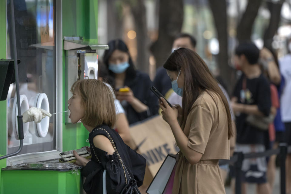 A woman has her throat swabbed for a COVID-19 test at a coronavirus testing site in Beijing, Saturday, Aug. 6, 2022. (AP Photo/Mark Schiefelbein)