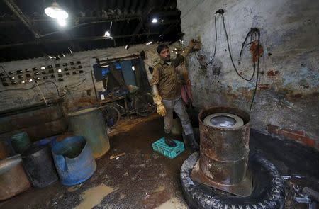 Reet Lal, a worker stands next to a machine used for drying auto parts inside a workshop in Faridabad, December 24, 2015. REUTERS/Adnan Abidi/Files
