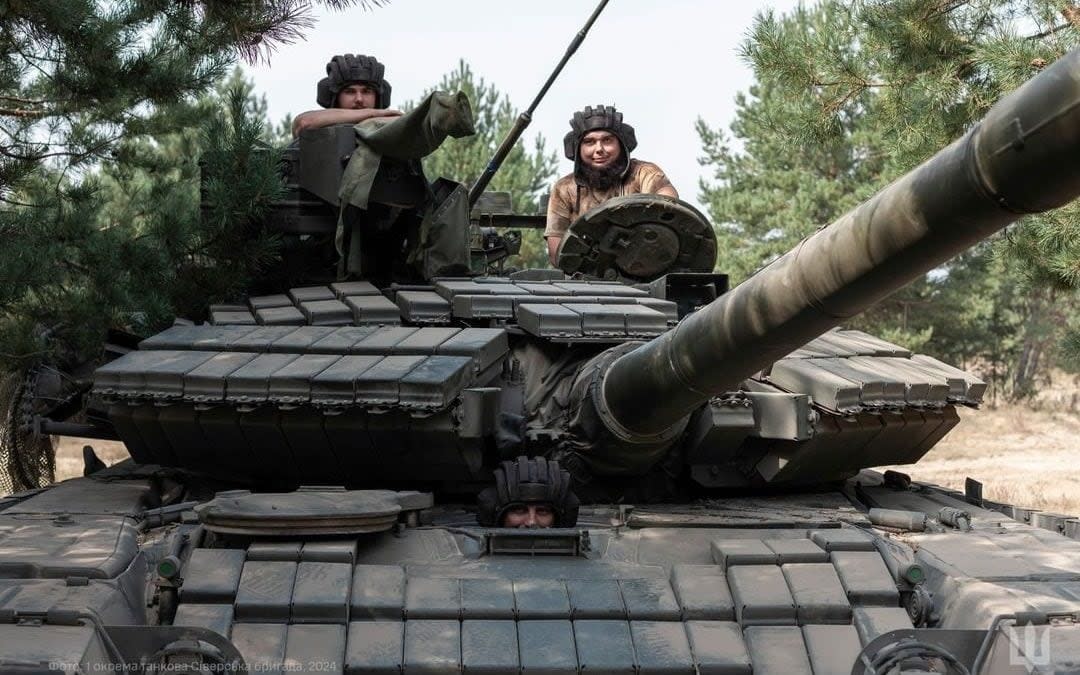 Two soldiers pose with a tank