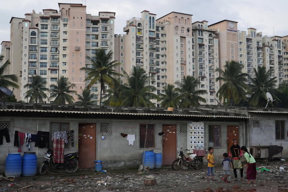 Children play in a poor neighborhood next to an upscale residential apartment building in Bengaluru, India, Wednesday, July 20, 2022. In this community, most people are from Assam state, many forced to migrate because of climate change and dreaming of a better future. (AP Photo/Aijaz Rahi)