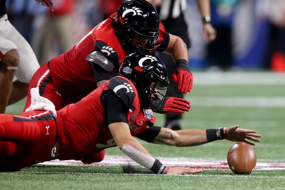 Cincinnati Bearcats quarterback Desmond Ridder (9) and Cincinnati Bearcats offensive lineman Vincent McConnell (77) dive for a fumble in the fourth quarter during the Chick-fil-A Peach Bowl against the Georgia Bulldogs, Friday, Jan. 1, 2021, at Mercedes-Benz Stadium in Atlanta, Georgia. The Georgia Bulldogs won, 24-21.