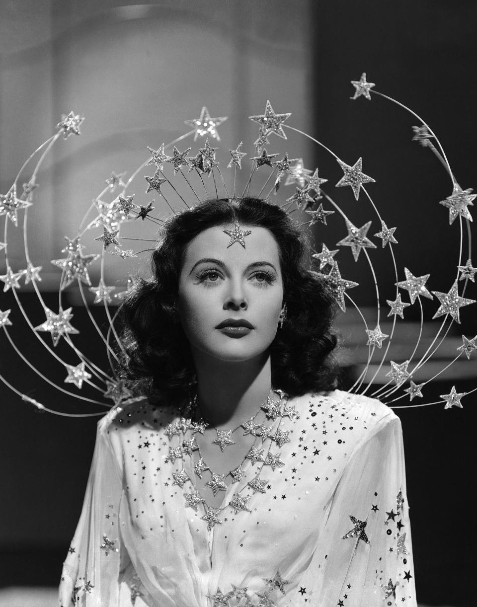 Hedy LaMarr wearing her famous Ziegfeld Girl outfit, which features a floating dress covered in glittering stars and an elaborate headdress made of wire, covered in more glittering stars