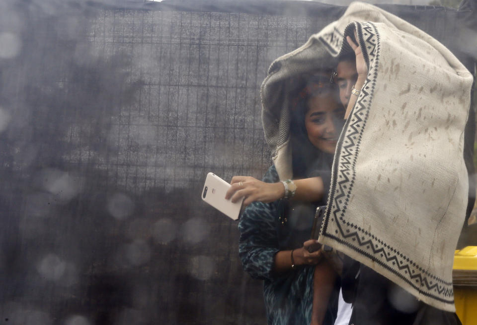 In this Thursday, Aug. 22, 2019 photo, Saudi tourists take selfies in heavy rain, during the al-Soudah festival, in Abha, southwest Saudi Arabia. The weather in August in the village of al-Soudah, located in Asir province, is a comfortable 70 F (22 C) unlike the capital, Riyadh, or the coastal city of Jiddah, where temperatures exceed 105 F (43 C) throughout the summer. In the winter, parts of the mountain range see snow. (AP Photo/Amr Nabil)