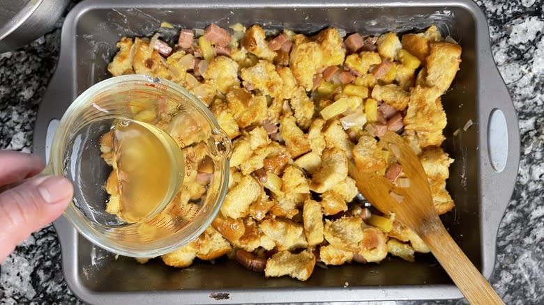 pouring stock on stuffing in pan