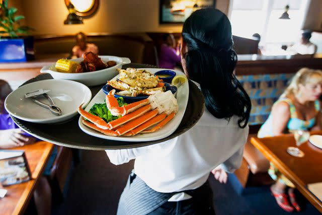 <p>Michael Nagle/Bloomberg/Getty</p> A waitress carries a lobster kettle and a crab trio dish at a Red Lobster restaurant in Yonkers, New York