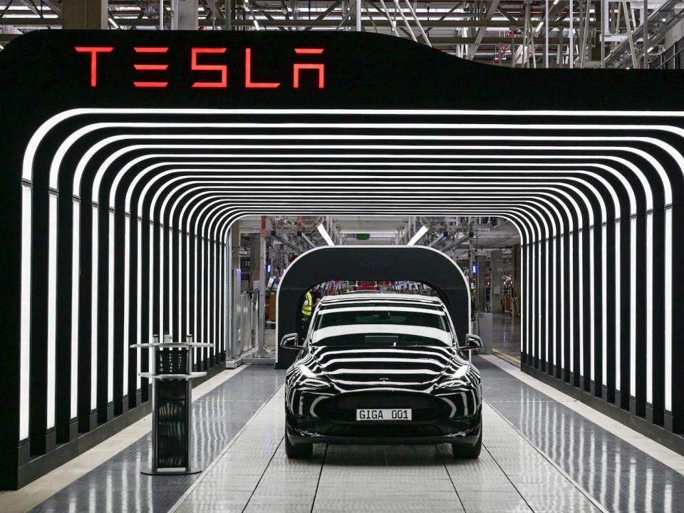 A Model Y electric vehicle stands on a conveyor belt at the opening of the Tesla Gigafactory Berlin Brandenburg.