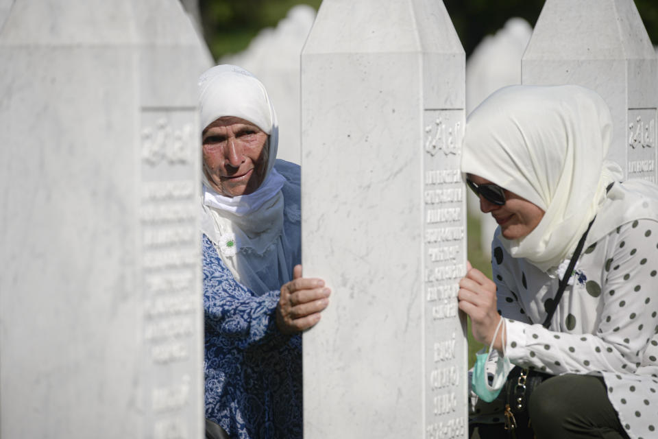 Mujeres acarician una lápida en Potocari, cerca de Srebrenica, Bosnia, sábado 11 de julio de 2020. Los cuerpos de nueve hombres fueron hallados, identidicados y enterrados al conmemorar Bosnia el 25 aniversario de la masacre de Srebrenica por el ejército serbio. Más de 10.000 bosnios perecieron en la masacre que duró 10 días. (AP Foto/Kemal Softic)