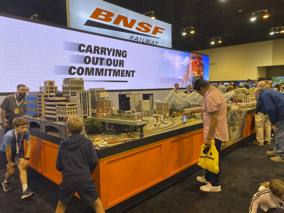 People look at a model train display at the BNSF railroad company's booth at Berkshire Hathaway's annual meeting in Omaha, Neb., on Friday, May 5, 2023. Negotiators for the union that represents engineers remain frustrated with the demands BNSF is making in negotiations over paid sick time instead of just granting the benefit. Engineers still haven't secured sick time at any of the major freight railroads even though a number of smaller rail unions have reached sick time deals in 2023. (AP Photo/Josh Funk)