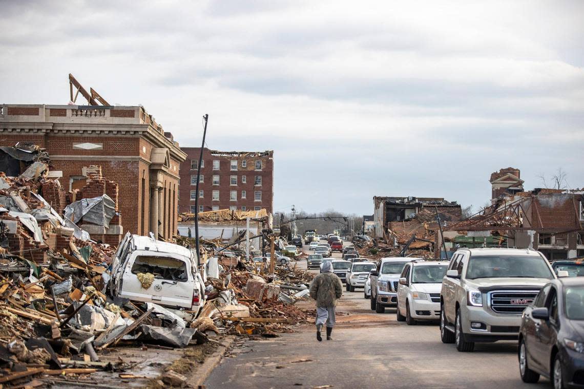 Vehicles drive along West Broadway in downtown Mayfield, Ky., a day after the community was hit by a tornado. Saturday, Dec. 11, 2021