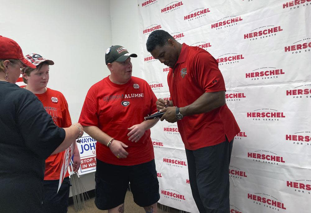 Georgia Republican Senate candidate Herschel Walker signs a soda bottle commemorating the University of Georgia’s 1980 national football championship on Saturday, May 21, 2022 in Columbus, Ga. Walker’s football fame has drawn voters to his events throughout his campaign against Democratic incumbent Raphael Warnock. (AP Photo/Jeff Amy)