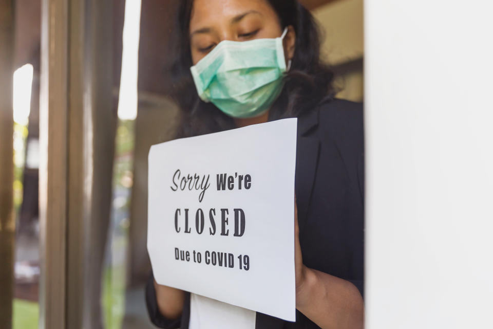 Portrait shot of business owner putting a closing down poster into a window during Covid 19 outbreak