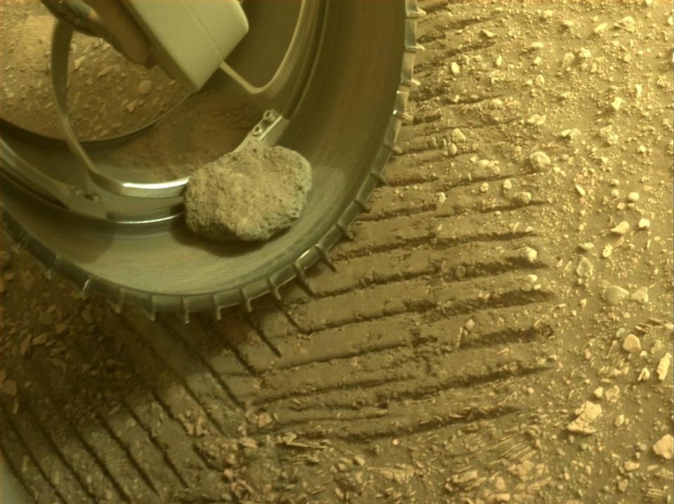 The same rock still in the rover’s front left wheel on sol 413. Image taken April 19, 2022.
