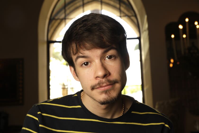 A close-up of a young man with a mustache and small beard