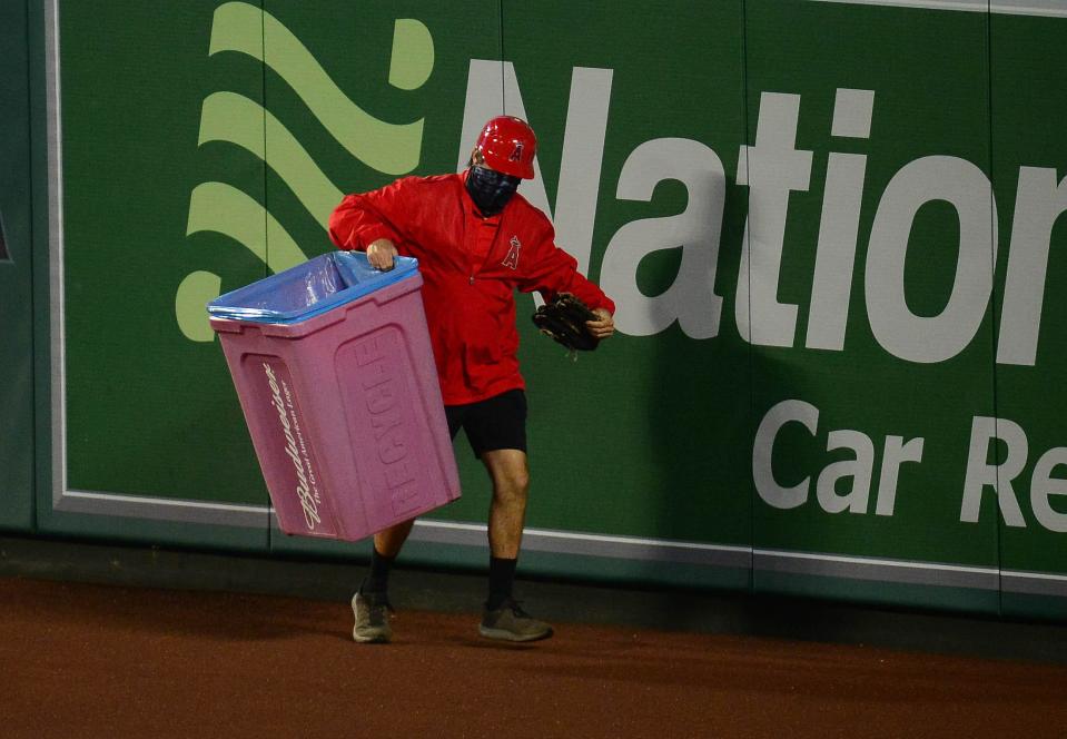 Apr 5, 2021; Anaheim, California, USA; A stadium worker removes a trash can that was thrown onto the field during the eighth inning at Angel Stadium. Mandatory Credit: Gary A. Vasquez-USA TODAY Sports