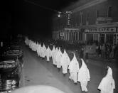 <p>Members of the Ku Klux Klan wear white hoods and robes as they march in single file around the town square in Swainsboro, Ga., on their way to the Emanuel County Courthouse where they burned a cross on the lawn, Feb. 3, 1948. (Photo: AP) </p>