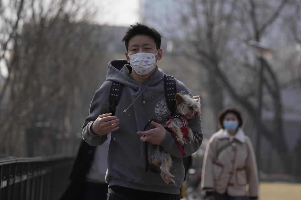 A man wearing a mask walks down a Beijing street on Sunday, March 20. China is battling its worst COVID-19 outbreak in two years.