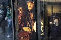 Shoppers, some wearing a face mask to help curb the spread of the coronavirus are reflected on a fashion boutique's window panel as they walk through the capital city's popular shopping mall in Beijing, Monday, Oct. 19, 2020. China’s shaky economic recovery from the coronavirus pandemic is gaining strength as consumers return to shopping malls and auto dealerships while the United States and Europe endure painful contractions. (AP Photo/Andy Wong)