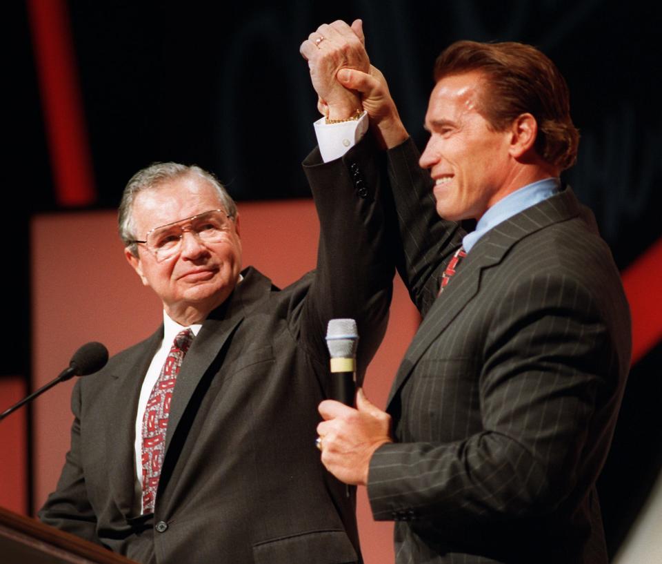 Bodybuilder Arnold Schwarzenegger, left, raises the hand of Jim Lorimer after surprising him at the Columbus Convention and Visitor's Bureau annual meeting on Feb. 4, 1998. Lorimer was receiving the bureau's annual hospitality award and Arnold flew in from Los Angeles to honor his friend.