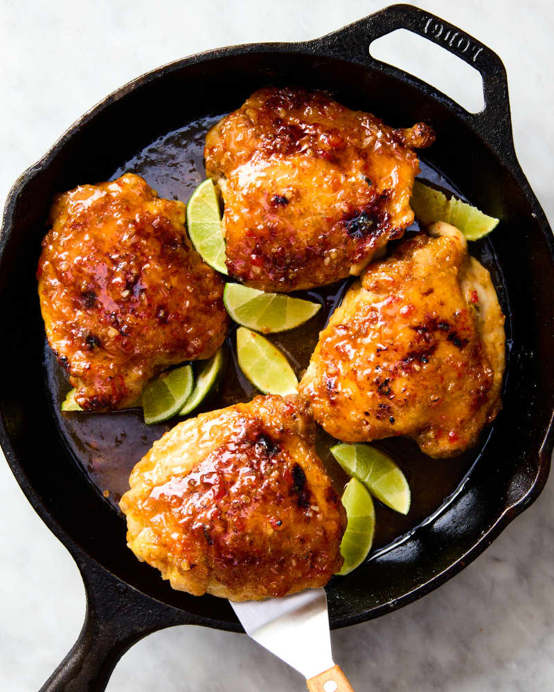 sweet chili chicken thighs in cast iron skillet with some lime wedges