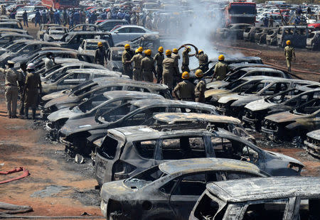 Firefighters extinguish smouldering cars after a fire broke out in a parking lot during the Aero India show at the Yelahanka Air Force Station in Bengaluru, India, February 23, 2019. REUTERS/Stringer