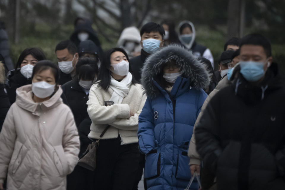 Commuters wearing face masks walk along a street in the central business district in Beijing on Jan. 12, 2023. China has announced its first overall population decline in recent years amid an aging society and plunging birthrate. (AP Photo/Mark Schiefelbein)