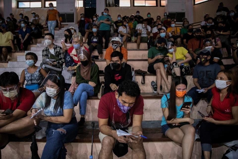 Filipinos use their smartphones while queueing for free vaccination against the coronavirus disease (COVID-19) at San Andres Sports Complex in Manila, Philippines, July 21, 2021. REUTERS/Eloisa Lopez
