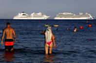 People visit Saint Rafael beach where a number of cruise ships are anchored for refueling and resupply, in southern coastal city of Limassol, Cyprus, on Wednesday, July 29, 2020. Cyprus' Tourism Minister Savvas Perdios says the country doesn't expect to receive this year more than 20-25% of the record 3.97 million holidaymakers it welcomed in 2019 as the coronavirus pandemic has so far shut out its key tourism markets. (AP Photo/Petros Karadjias)