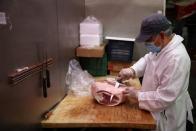 A butcher cuts meat in a supermarket in Manhattan, New York City