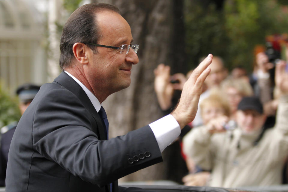 François Hollande, tout juste investi président de la République, salue la foule depuis sa voiture alors qu'il quitte le Palais de l'Elysée après la cérémonie d'investiture pour rejoindre l'Arc de Triomphe en remontant les Champs Elysées. AFP