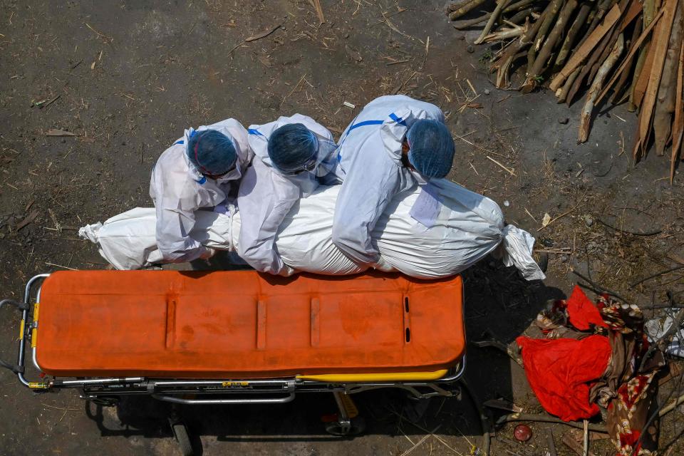 Family members and ambulance workers in PPE gear carry the body of a victim who died from COVID-19 complications to a cremation site in New Delhi, India on Tuesday.