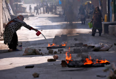 A Kashmiri woman pours water on burning debris after a protest in Srinagar against the recent killings in Kashmir, September 30, 2016. REUTERS/Danish Ismail