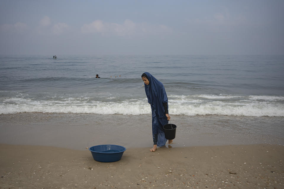 Palestinian woman collects seawater to wash clothes at the beach in Deir al Balah, Gaza Strip, on Thursday, November 2, 2023. (AP Photo/Fatima Shbair)
