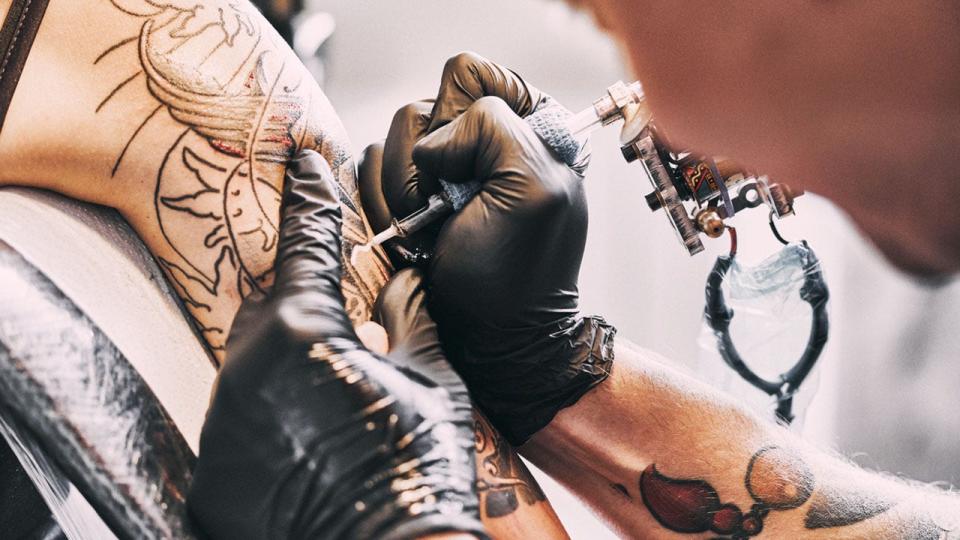 Tattoo Artist making a tattoo on a shoulder