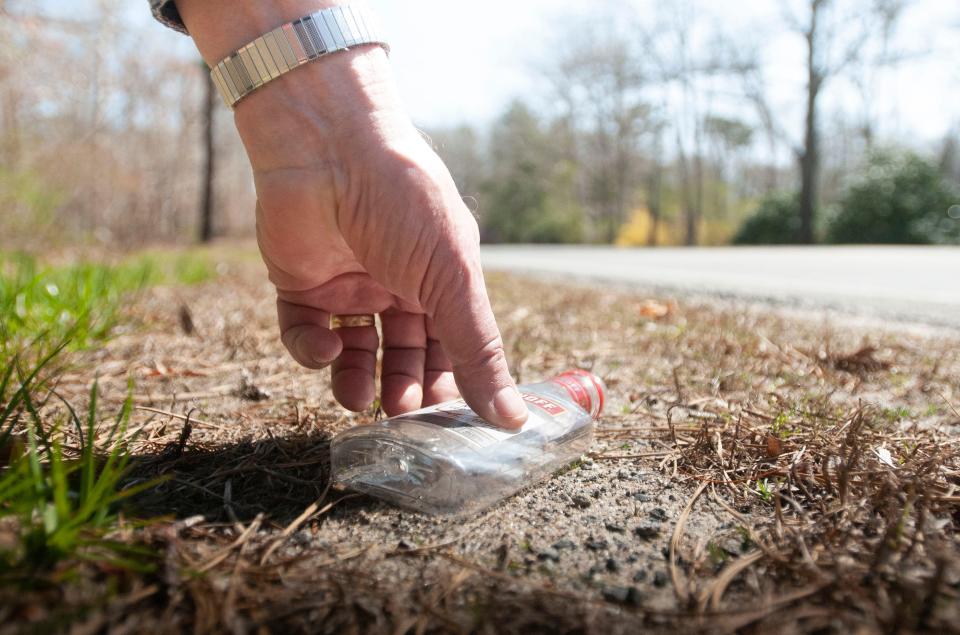 Sandwich resident Dan Tanner picks up a small Smirnoff vodka bottle on Monday along Quaker Meetinghouse Road. Tanner is sponsoring a ban on sales of nip bottles, or miniature alcohol bottles, in a warrant article on Monday at the Sandwich annual town meeting.