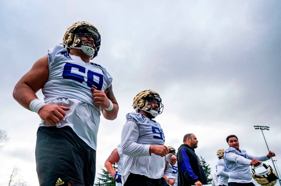 Washington’s Ulumoo Ale (68) jogs off the field with his fellow defensive lineman during spring practice on Wednesday, March 30, 2022, at Husky Stadium in Seattle, Wash.