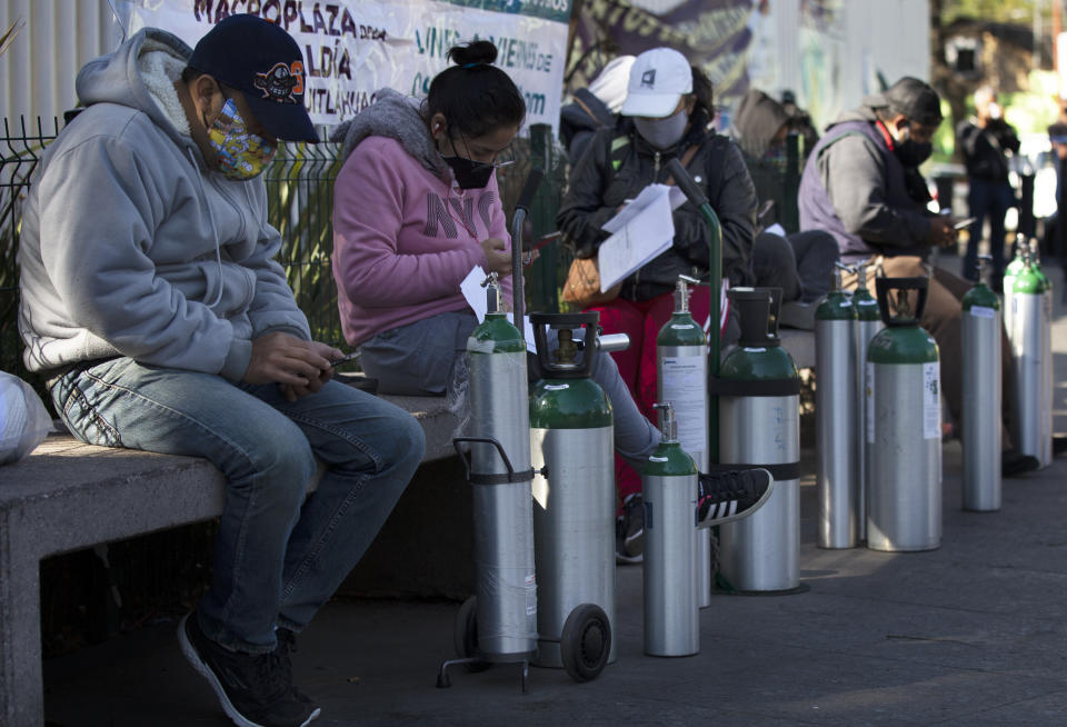 People wait to refill oxygen tanks for relatives sick with COVID-19 in the Iztapalapa district of Mexico City, on Tuesday, Jan. 26, 2021. The city is offering free oxygen refills for patients with COVID-19. (AP Photo/Marco Ugarte)