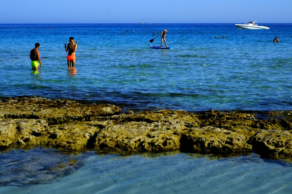 Tourist enjoy the sea at 'Landa' beach in the southern coastal resort of Ayia Napa in southeast Mediterranean island of Cyprus, Sunday, May 29, 2022.Hundreds of Russian and Ukrainian Orthodox faithful visiting Cyprus would stream daily past the icon of the Virgin Mary at Kykkos Monastery to venerate the relic that tradition dictates was fashioned by Luke the Evangelist and blessed by the Virgin herself. But a European Union ban on flights to and from Russia as a result of Russia's invasion of Ukraine has meant a loss of 800,000 vacationers - a fifth of all tourists to Cyprus in record-setting 2019. (AP Photo/Petros Karadjias)