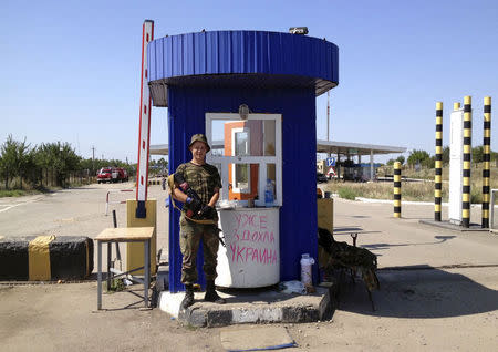 An armed pro-Russian separatist stands guard at a border checkpoint near the territory of Russia in Izvaryne, Luhansk region, July 31, 2014. REUTERS/Maria Tsvetkova