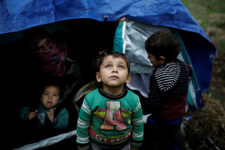 A Syrian refugee boy stands in front of his family tent at a makeshift camp for refugees and migrants next to the Moria camp on the island of Lesbos, Greece, November 30, 2017. REUTERS/Alkis Konstantinidis