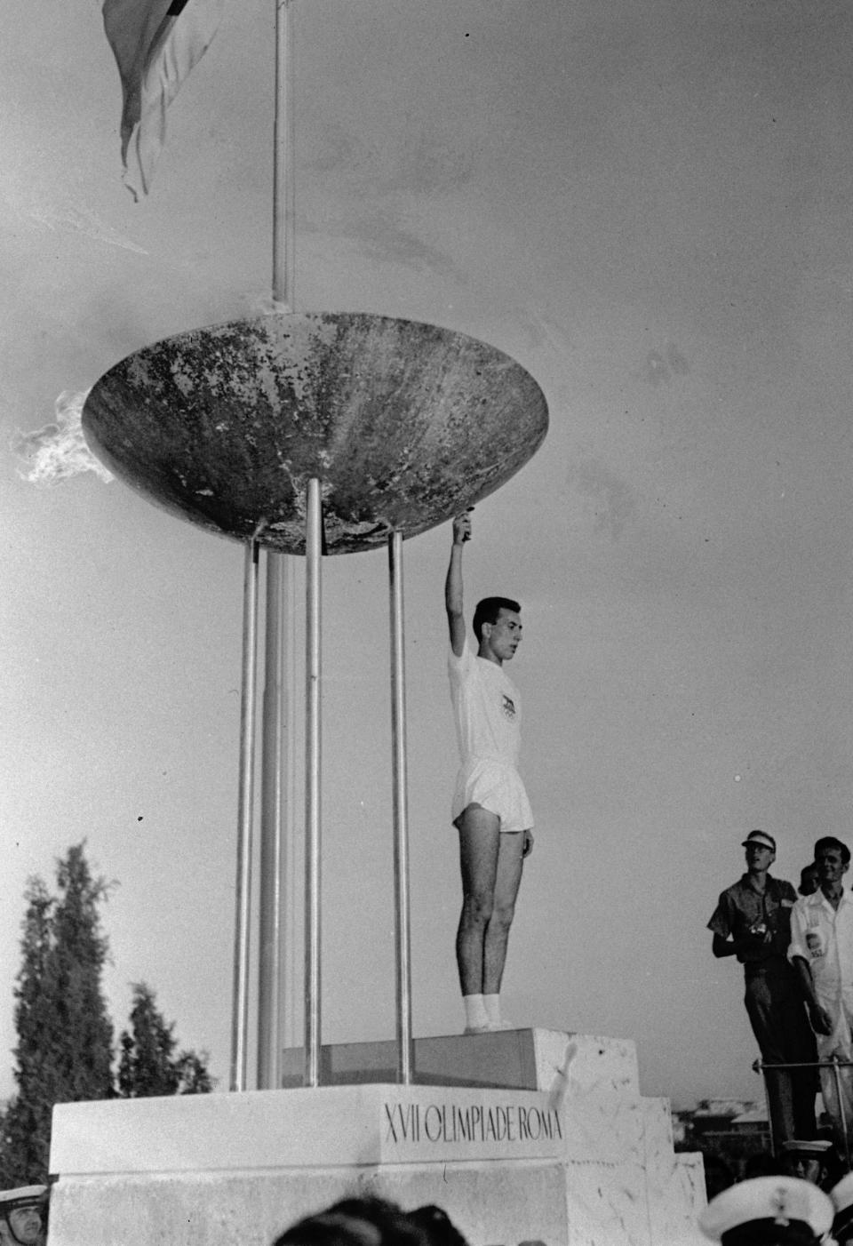 Italian student Giancarlo Peris holds the torch after lighting the Olympic flame in the tall tripod brazier on the perimeter of the Olympic Stadium in Rome, Aug. 25, 1960, at the formal opening of the XVII modern Olympiad. (AP Photo)