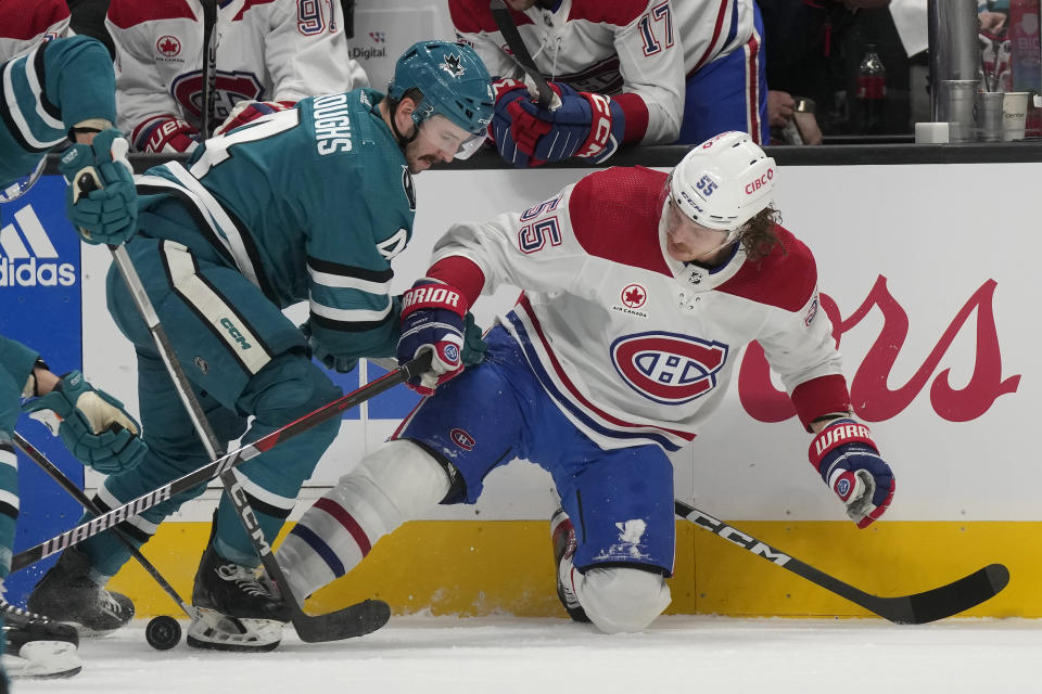 Montreal Canadiens left wing Michael Pezzetta (55) reaches for the puck under San Jose Sharks defenseman Kyle Burroughs during the second period of an NHL hockey game in San Jose, Calif., Friday, Nov. 24, 2023. (AP Photo/Jeff Chiu)