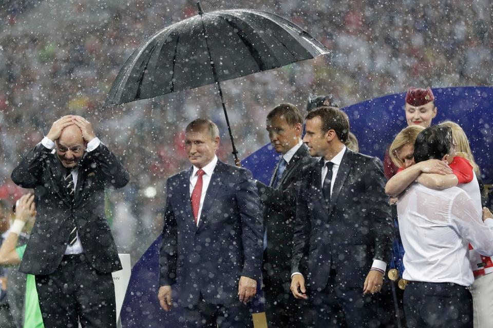 Russian President Vladimir Putin stands under an umbrella while those around him get soaked: AP