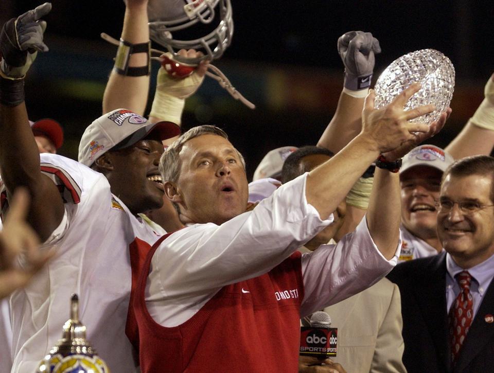 Ohio State coach Jim Tressel holds up the national championship trophy after the Buckeyes beat Miami 31-24 in two overtimes in the Fiesta Bowl, Jan. 3, 2003, in Tempe, Ariz.