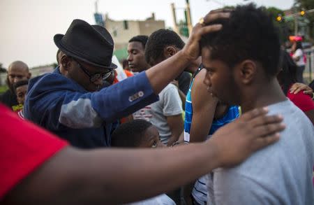 Pastor Brooks (L) places his hand on the head of an attendee during a prayer at a candlelight vigil against gun violence in the Englewood neighborhood in Chicago, Illinois, United States, July 3, 2015. REUTERS/Jim Young