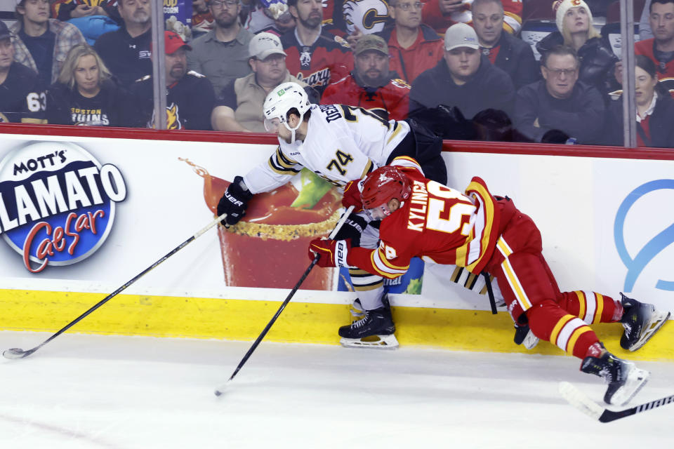 Boston Bruins' Jake DeBrusk, left, keeps the puck away from Calgary Flames' Oliver Kylington during the second period of an NHL hockey game Thursday, Feb. 22, 2024, in Calgary, Alberta. (Larry MacDougal/The Canadian Press via AP)
