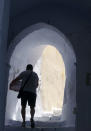 A man carries provisions up a steep alleyway in the compact, hilltop white village of Pyrgos on Santorini island, Greece, on July 1, 2021. Pyrgos sits removed from the tourist trail in the bucket-list island destination, among volcanic vineyards that grow the native grape Assyrtiko. (AP Photo/Giovanna Dell’Orto)