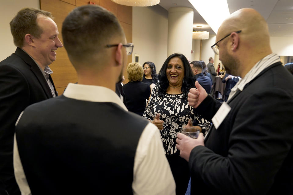 Shobha Surya, center, talks with coworkers at her company holiday party on Friday, Dec. 9, 2022, in Schaumburg, Ill. Say goodbye to virtual wine tastings, and bust out the karaoke. Love them or hate them, company holiday parties are back. Surya was so excited the party was back on this year that she picked out her black-and-white cocktail dress two months in advance. (AP Photo/Charles Rex Arbogast)